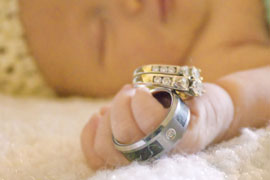 Newborn girl holding her parents wedding rings